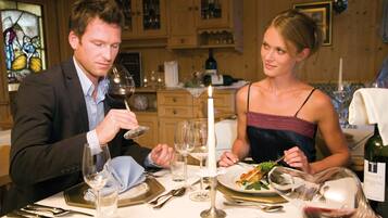 A dining table set with wine glasses, a candle, and plates of food.