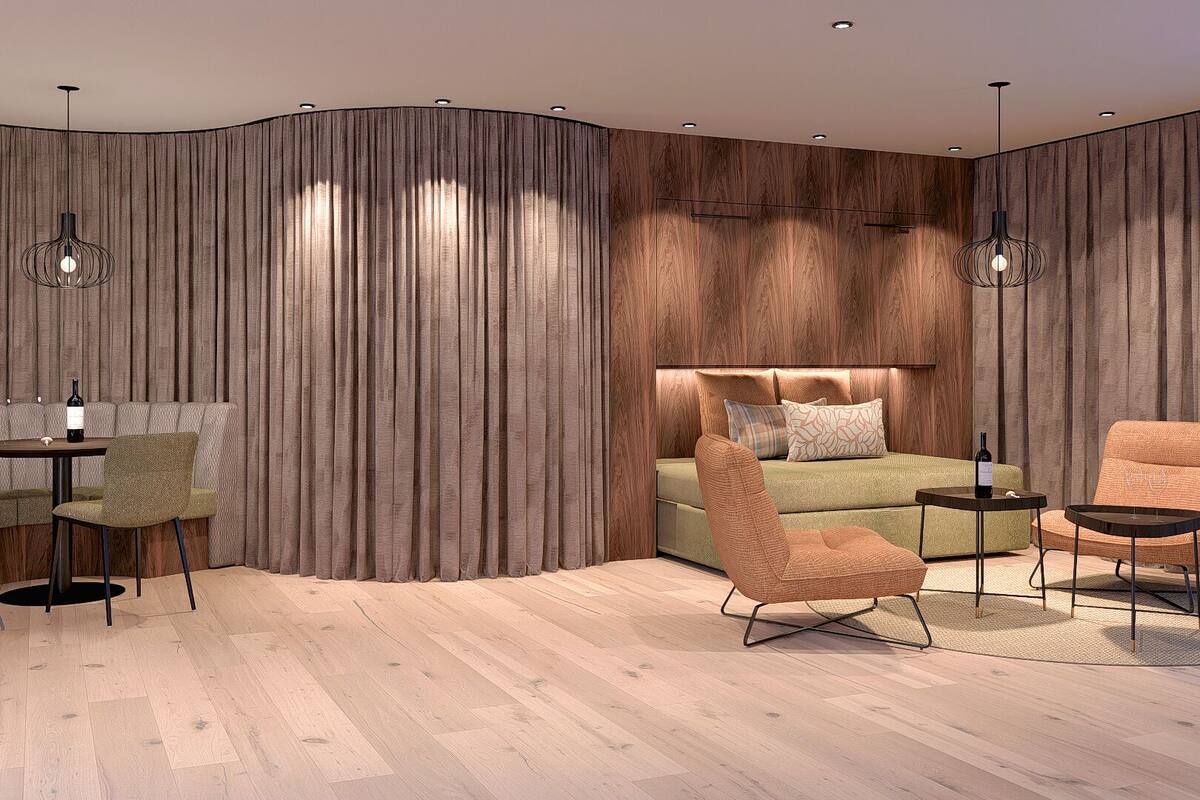 Un dormitorio moderno con pared curva, una cama con cabecera, dos sillones, una mesita y una lámpara de pie.