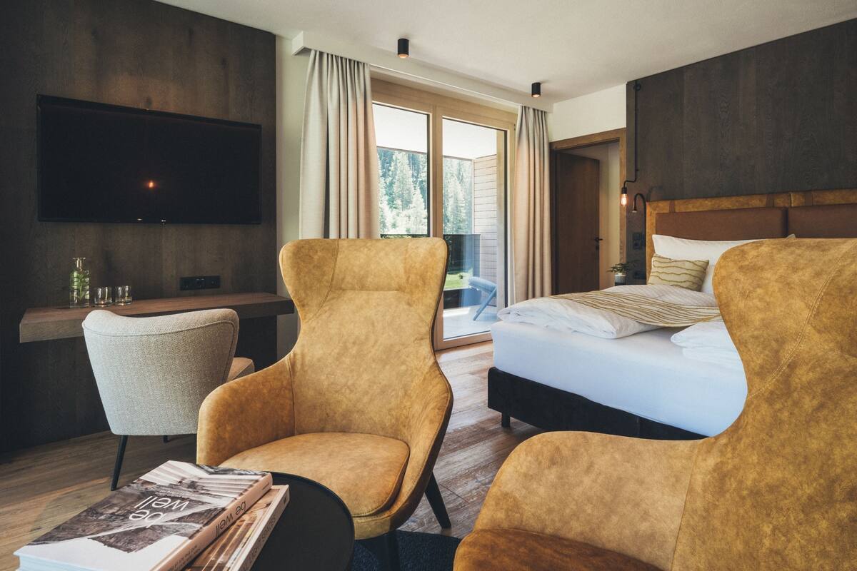 Una habitación de hotel moderna con una cama grande, dos sillones, un escritorio y un televisor.
