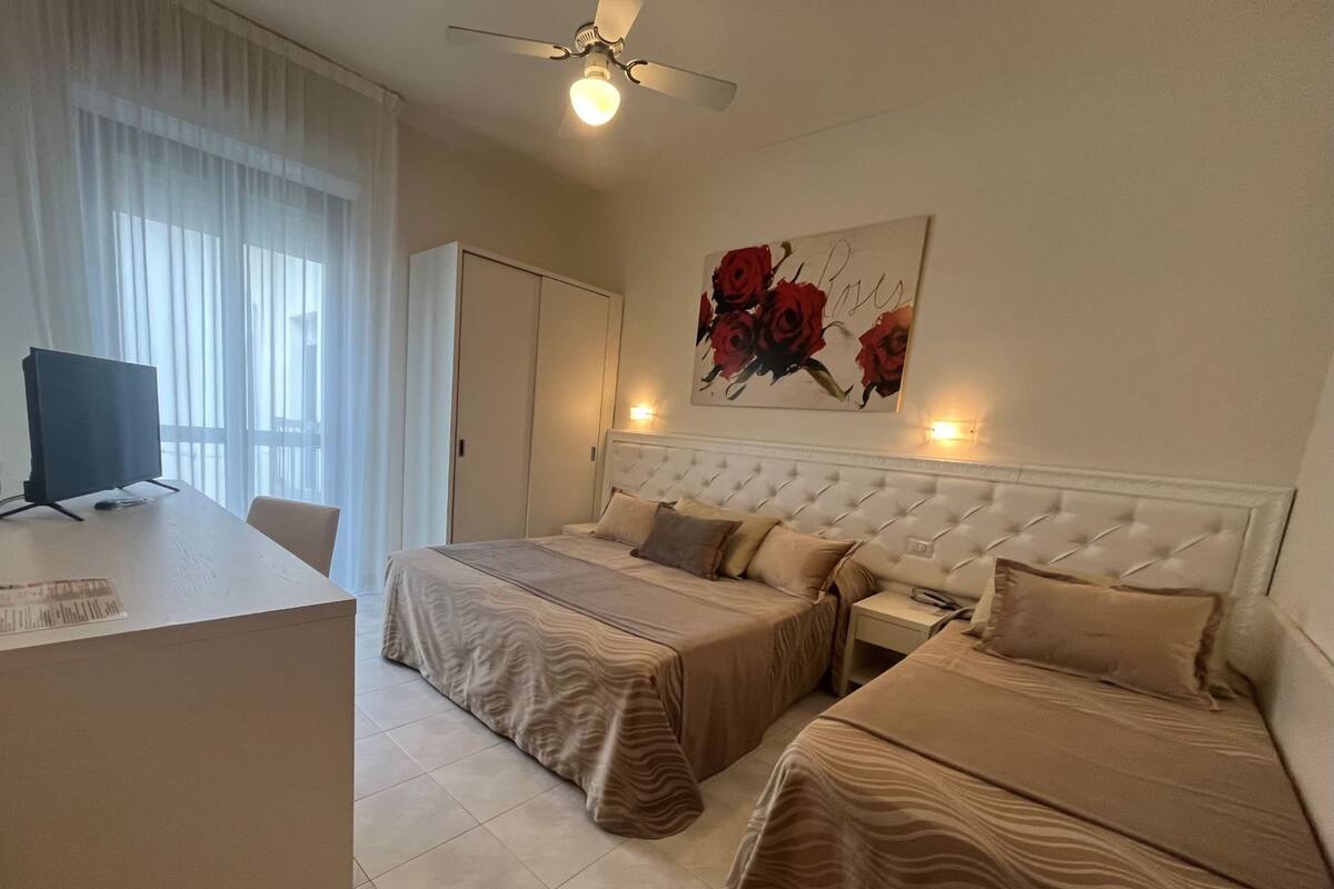 A hotel room with two beds, a desk, and a ceiling fan.
