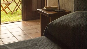 Una habitación con cama, una mesa con lámpara, y una puerta que da a un espacio exterior con mesa y sillas.