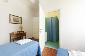 A room with two beds, a desk with a chair, a framed picture on the wall, and a bathroom visible through an open door. - Agriturismo Quercesecca - Nature & Relax  (Grosseto)
