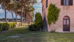 Un edificio de ladrillo con una escalera, un pequeño jardín y árboles.