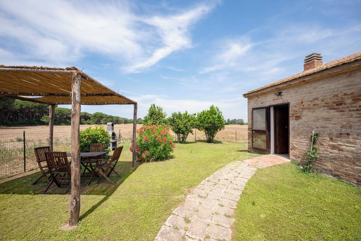 A patio with a table and chairs, a brick building, and a stone pathway.