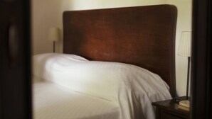 Een bed met hoofdbord, een bedlampje en een nachtkastje met een boek.
