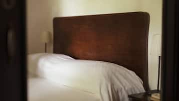 Uma cama com cabeceira, abajur e mesa de cabeceira com um livro.