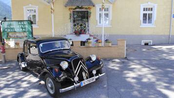 A vintage black car parked in front of a yellow building with a sign reading "Hotel Garnis Hubertus Hallenbad".