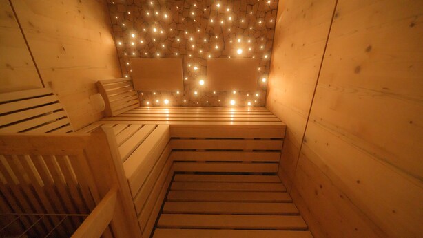 A sauna with wooden benches and a ceiling adorned with string lights. - Hotel Garni Hubertus (Fulpmes)