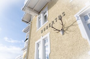 A building with the name "HUBERTUS" and a mounted deer head on the facade. - Hotel Garni Hubertus (Fulpmes)