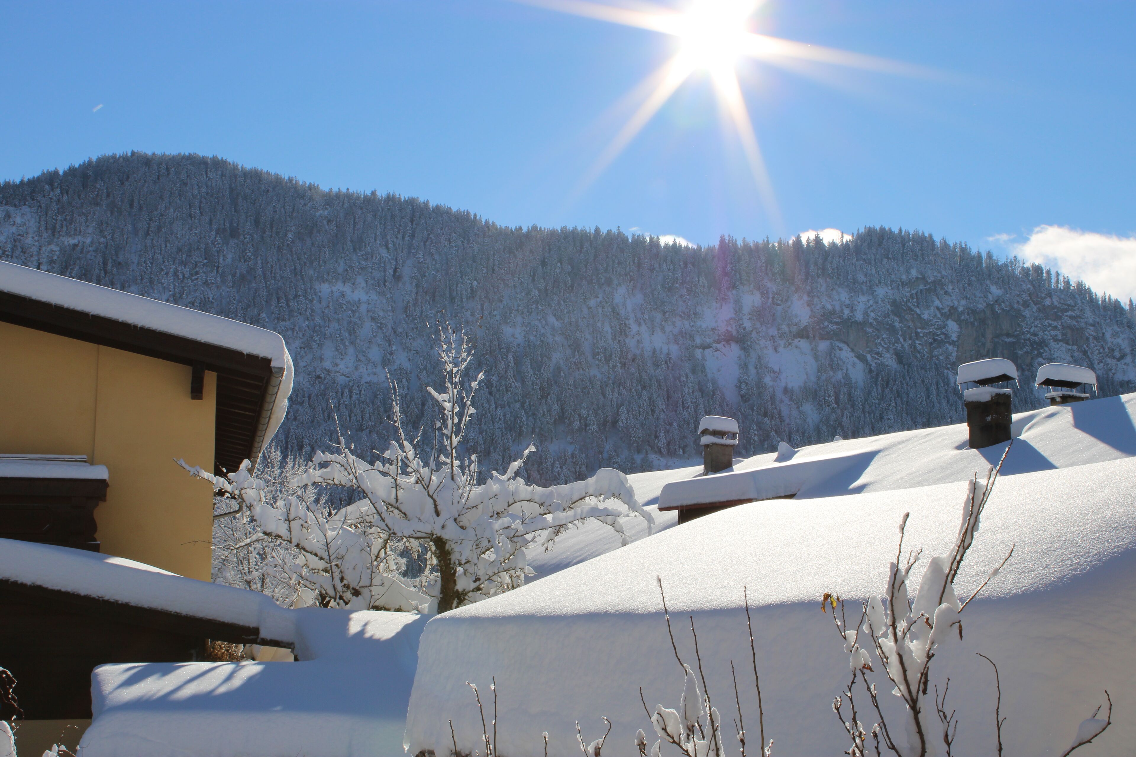 A snow-covered mountain with a clear sky and a bright sun.