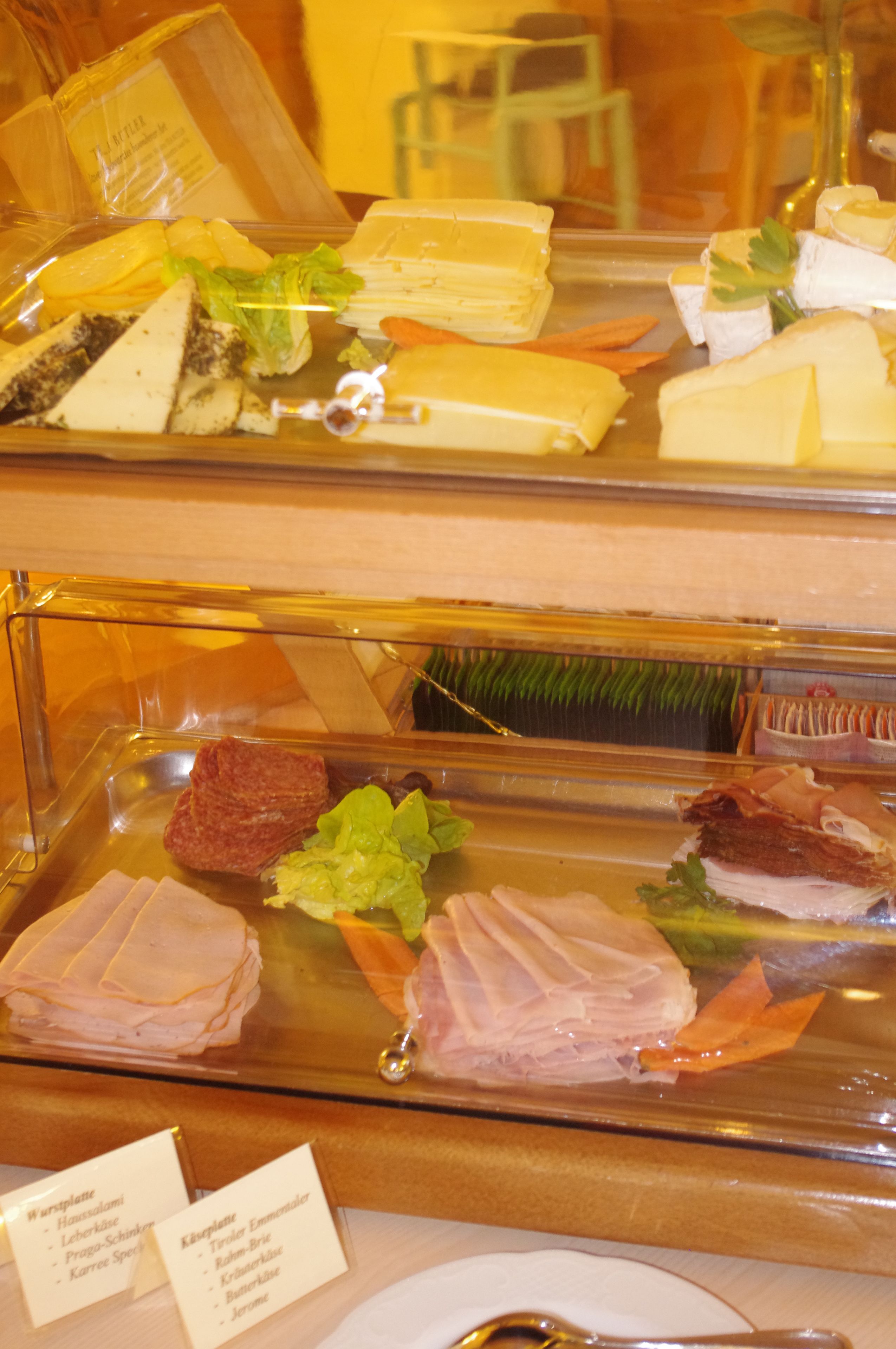 Un bufé con diferentes tipos de comida, incluyendo carnes, quesos y ensaladas.