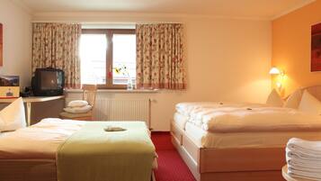 Une chambre d’hôtel avec deux lits, un bureau avec une télévision, une chaise, un radiateur et une lampe.