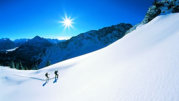 Un paysage de montagne enneigé avec deux skieurs dévalant une pente.