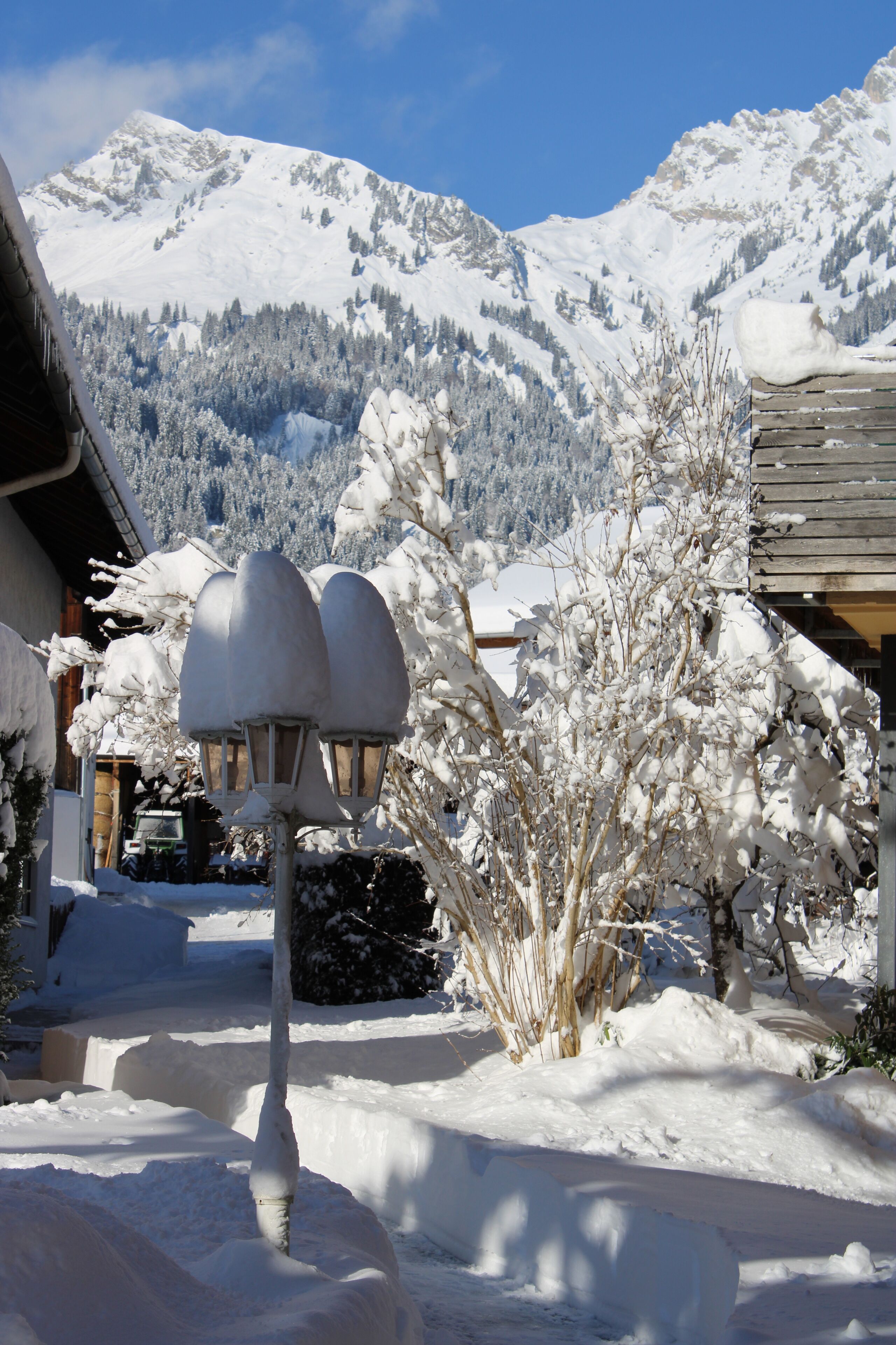 A snow-covered mountain landscape with a wooden building and a snow-covered lamp post.