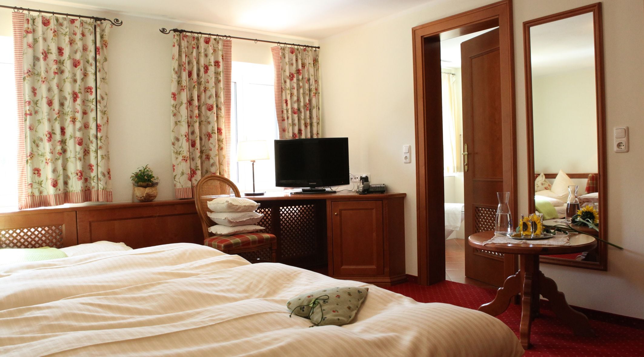 Un dormitorio con cama, televisor, escritorio y espejo.