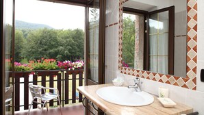 Ein Badezimmer mit einem großen Fenster, einem Waschbecken und einem Spiegel.