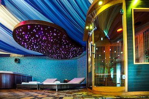 Una habitación con una cama, una mesita pequeña y un diseño de techo único con luces que parecen estrellas.