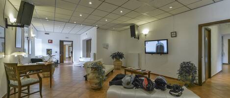 A spacious living area with a sofa, chairs, a television, and a dining area with a table and chairs.