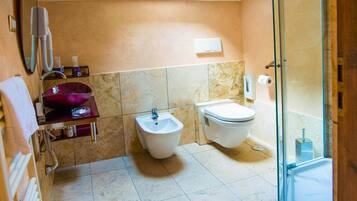 Un bagno con bidet, toilette e cabina doccia in vetro.