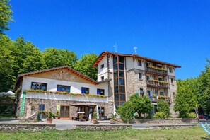 Un immeuble de deux étages avec une façade en pierre, de grandes fenêtres et des balcons ornés de jardinières.