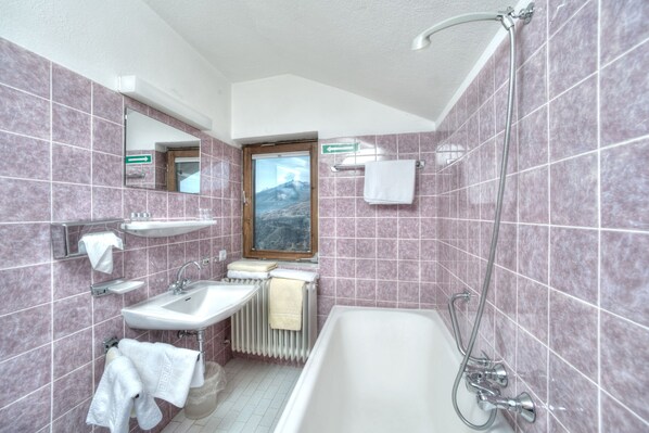 Une salle de bain avec une baignoire, deux lavabos, un miroir et une fenêtre donnant sur la montagne.