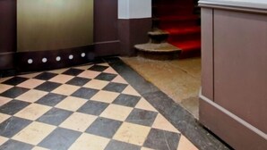 A hotel entrance with a checkered floor, a large sign, and a staircase. - Hôtel du Dauphin (Lyon)