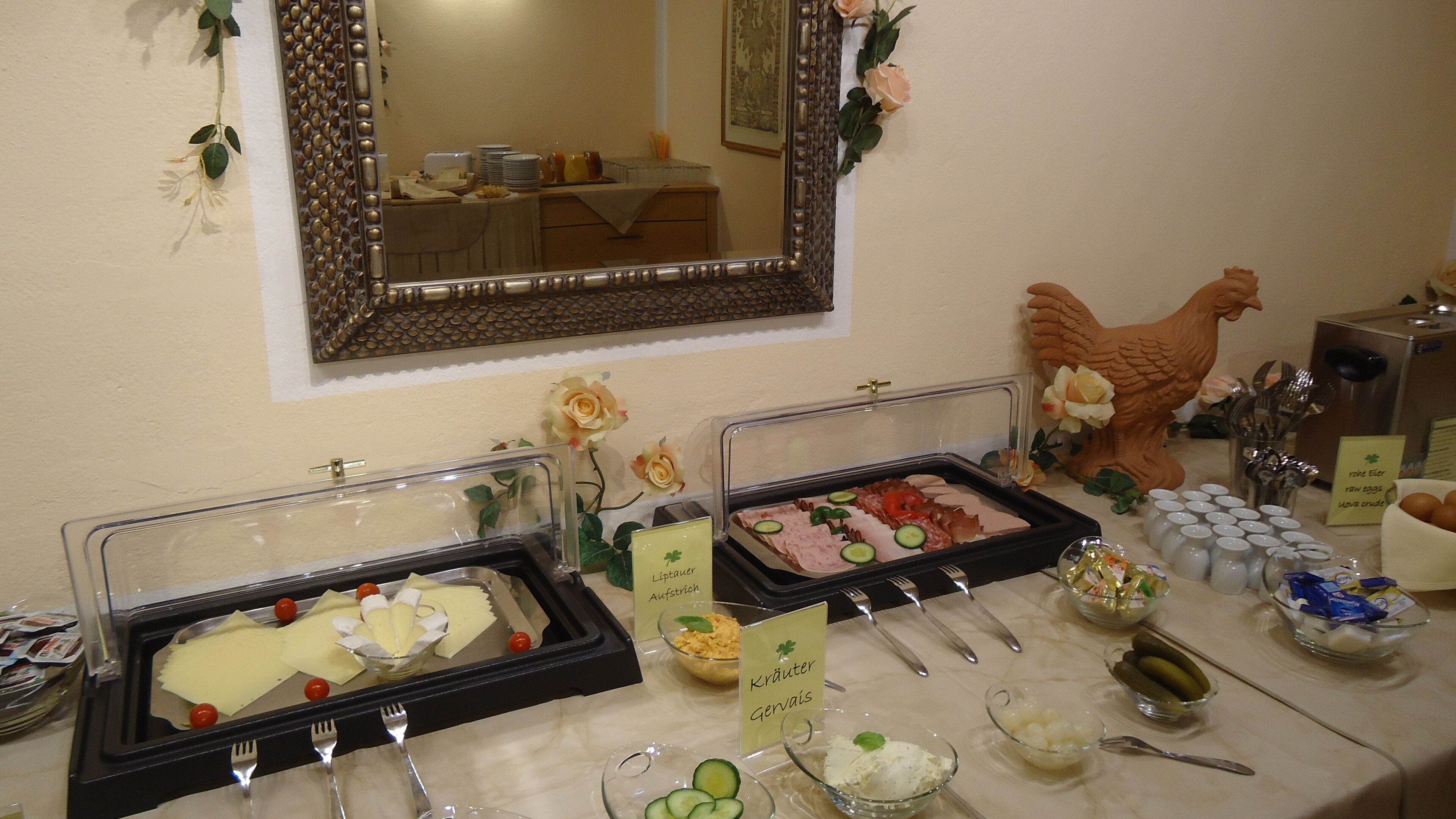 Ein Buffet mit verschiedenen Speisen und Geschirr, inklusive eines Schildes mit den Aufschriften 'Lippeauer' und 'Kräuter'.