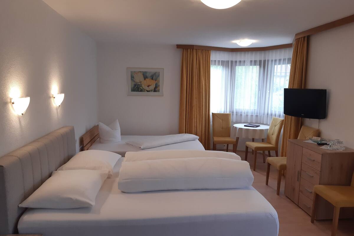 Une chambre d’hôtel avec un grand lit, deux tables de chevet, un bureau avec une chaise, une télévision et un tableau au mur.
