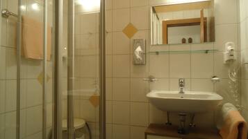 A bathroom with a glass shower enclosure, a sink, and a mirror.