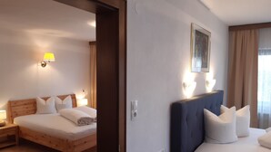 Une chambre d’hôtel avec deux lits, des têtes de lit en bois, du linge de lit blanc et des lampes fixées au mur.