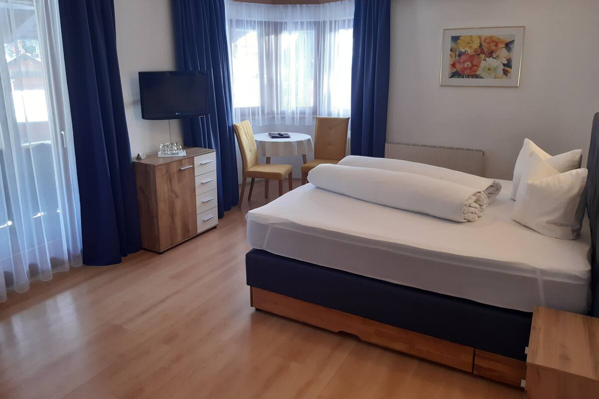 Une chambre d’hôtel avec un lit, un bureau, une chaise, une télévision et un tableau au mur.