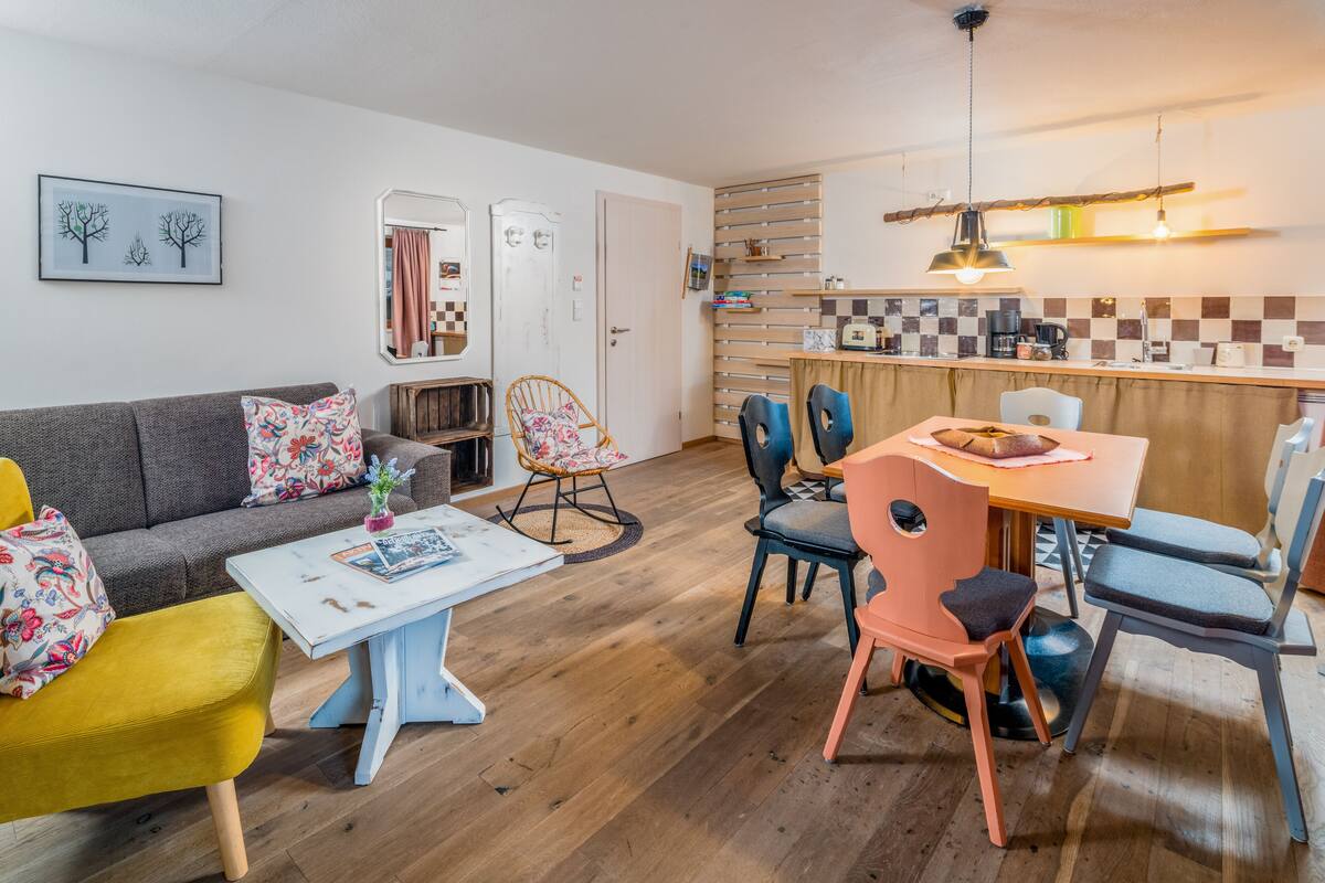 Una sala de estar acogedora con sofá, sillones, una mesa de centro y un comedor con mesa y sillas.