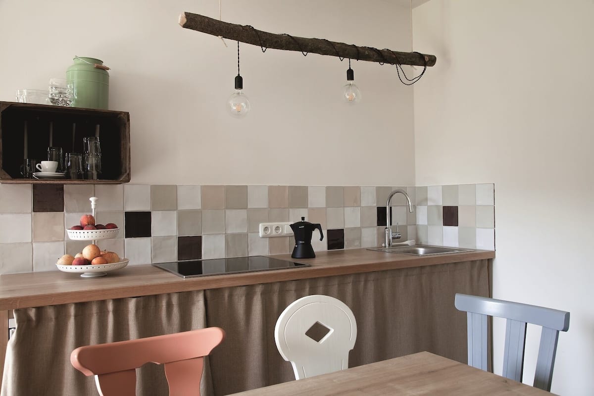 Una cocina con encimera de madera, un lavamanos y una zona de comedor con sillas.
