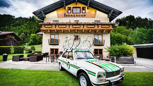 A hotel with a wooden facade, balconies, and a white car parked in front. - Hotel Tannenhof (Waengle)