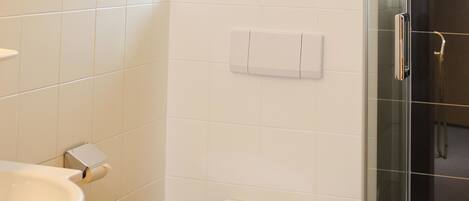 A bathroom with a white sink, toilet, and glass shower enclosure.