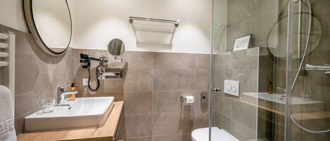 A modern bathroom with a glass-enclosed shower, a wooden vanity, a large mirror, and a toilet.