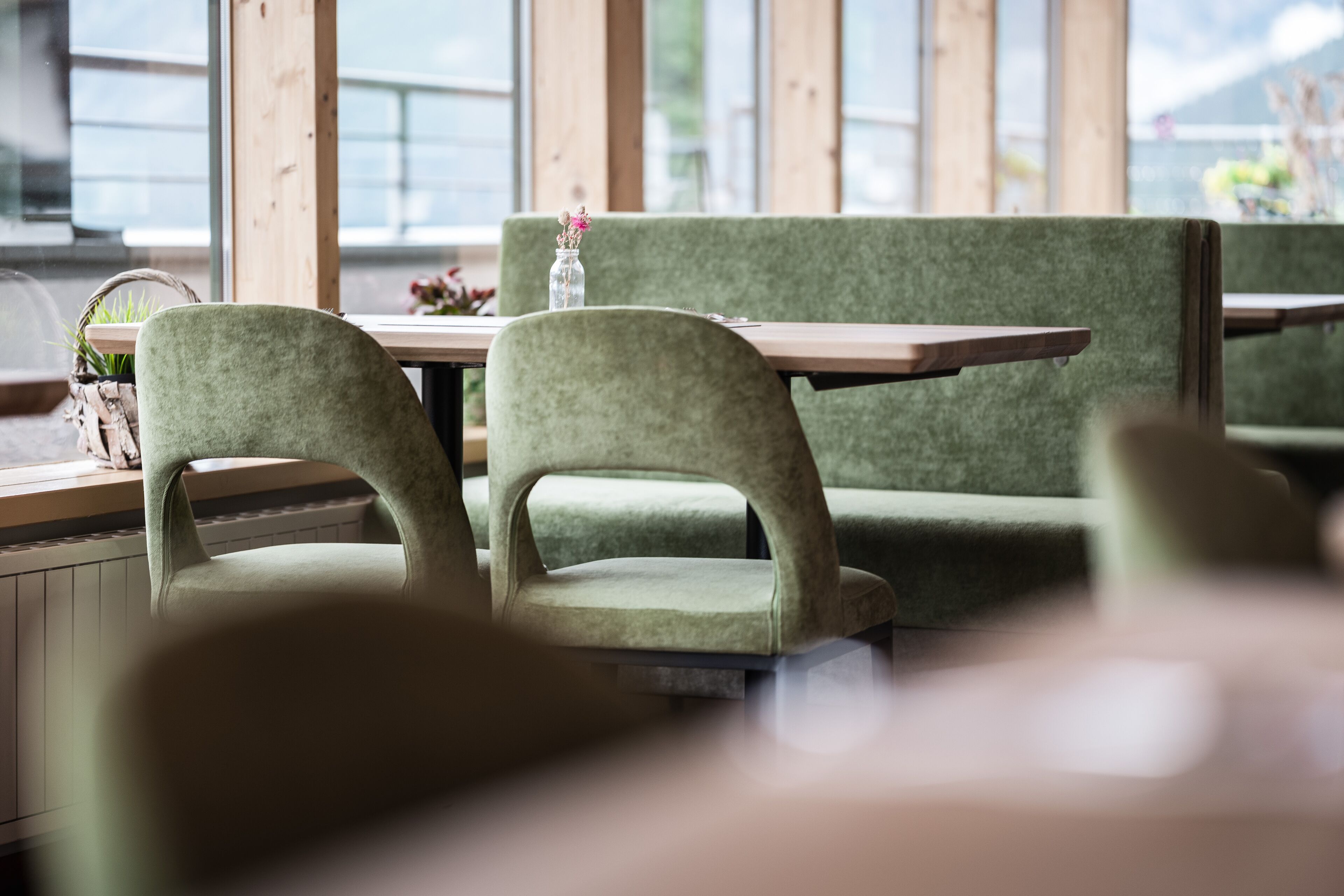 Un restaurante con asientos tapizados en verde y mesas de madera.