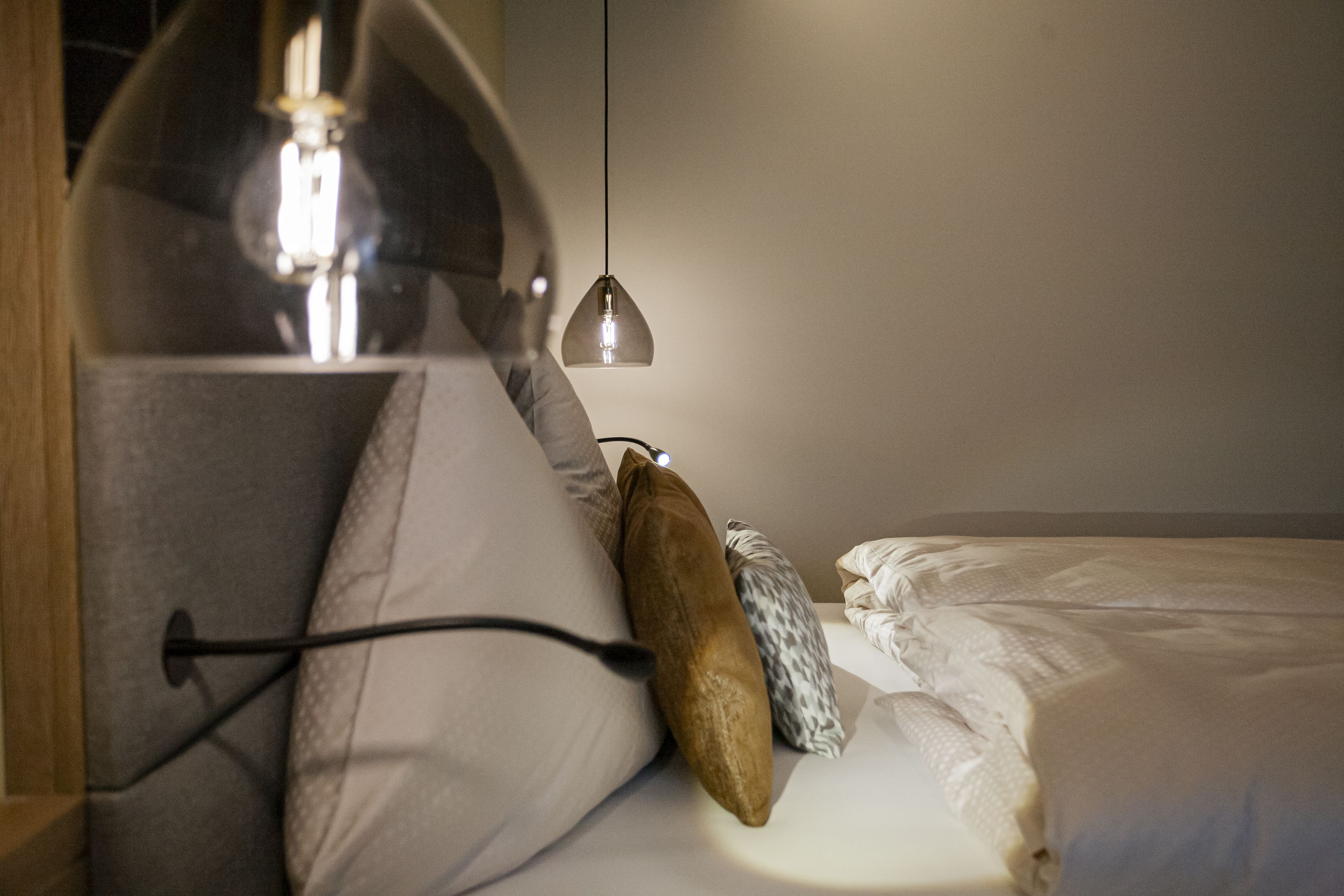 Ein ordentlich bezogenes Bett mit Kissen, einer Lampe und einem Nachttisch.
