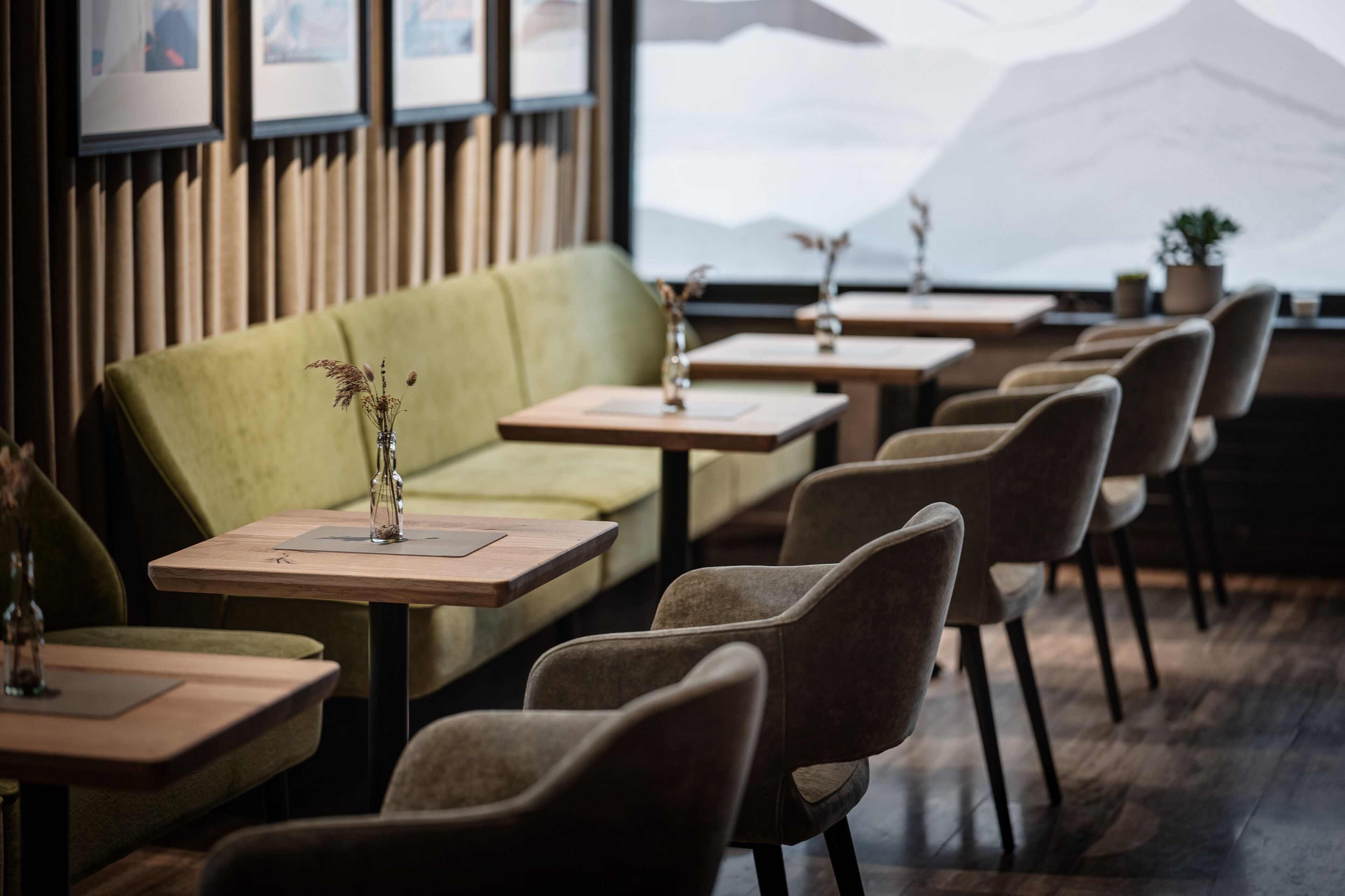 A restaurant with a green sofa, wooden tables, and chairs.