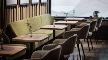 A restaurant with a green sofa, wooden tables, and chairs.
