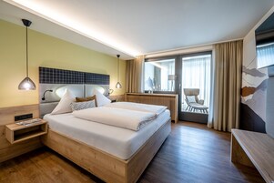Una habitación de hotel con una cama grande, mesitas de noche, un escritorio y vistas al exterior.