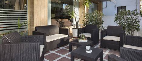 An outdoor seating area with wicker furniture and potted plants.