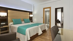 Ein Hotelzimmer mit einem großen Bett, Nachttischen, einem Schreibtisch und einem Sessel.