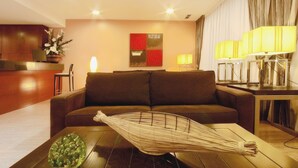 Ein modernes Wohnzimmer mit einem braunen Sofa, einem Glastisch und einem dekorativen Korbwannenstuhl.