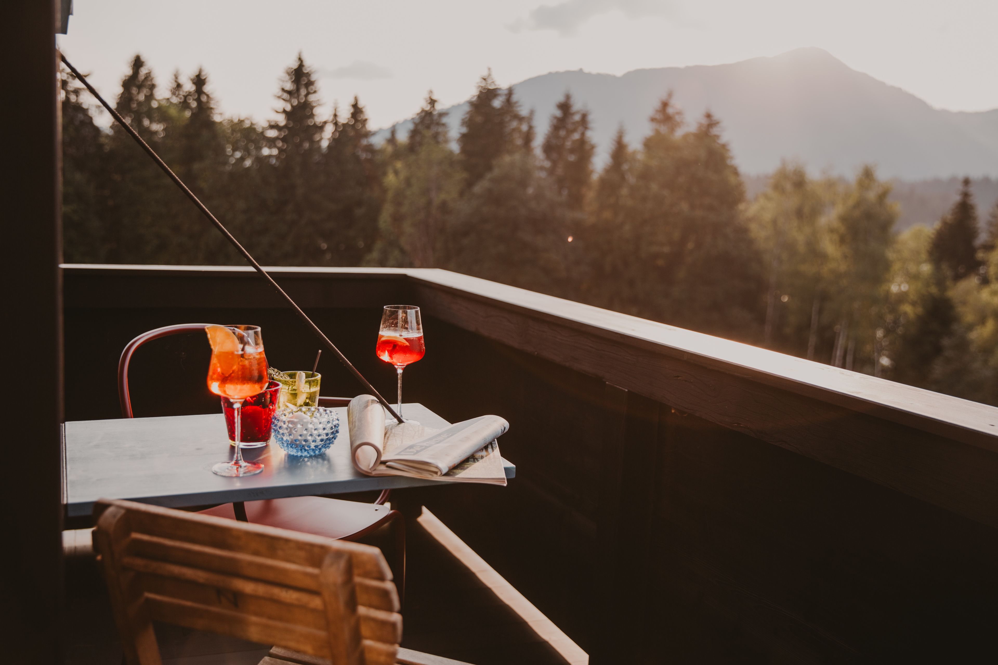 A balcony with a table set for two, featuring two drinks and a rolled-up menu.