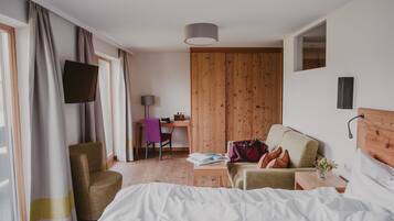 A hotel room with a bed, a desk, a chair, and a TV.