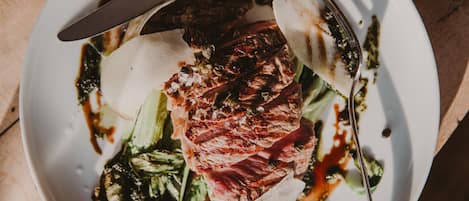 A plate of food with steak, greens, and sauce.