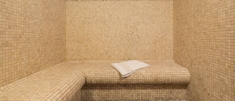 A small, tiled room with a bench and a pair of shoes on the floor.