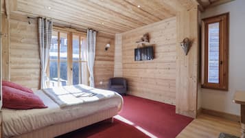 Ein Schlafzimmer mit Holzwänden, einem Bett, einem roten Teppich und einem Vorhangfenster.