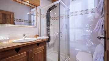 Ein modernes Badezimmer mit einer gläsernen Duschkabine, einem Holzwaschtisch mit Waschbecken und einer Toilette.